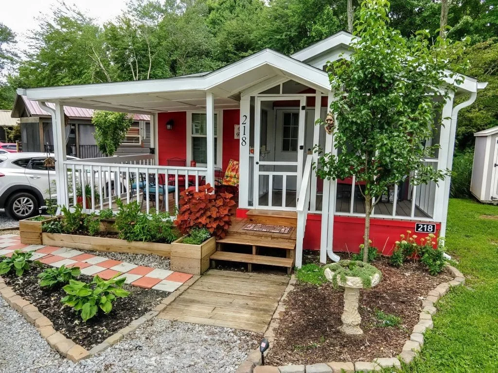 Exterior view of the Crimson Poppy tiny home with landscaped garden and covered porch in Flat Rock, North Carolina.