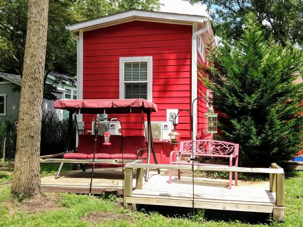 Private backyard featuring a relaxing swing and outdoor seating behind the Crimson Poppy tiny home.