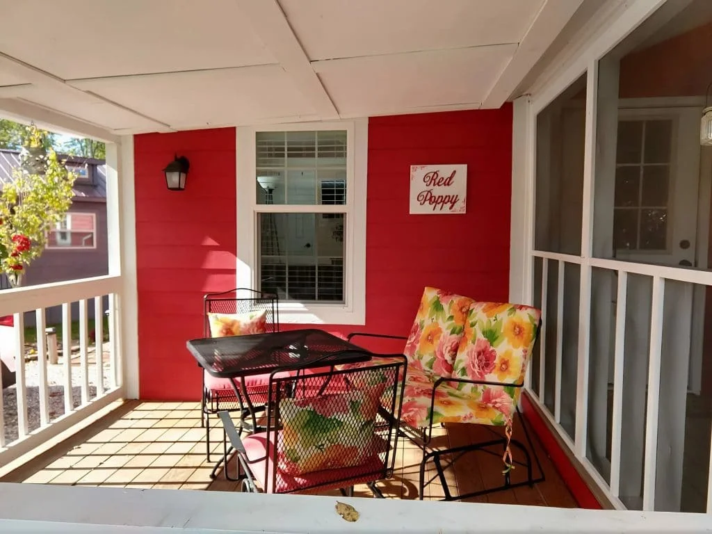 Covered front porch with outdoor seating at the Crimson Poppy tiny home in the Easy Life Community.