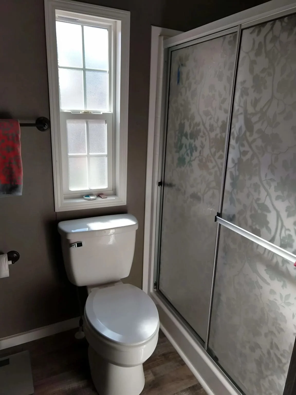 Bright bathroom with a walk-in shower, toilet, and frosted window inside the Crimson Poppy tiny home in Flat Rock, North Carolina.