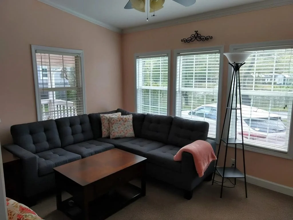 Cozy living room with comfortable seating, large windows, and natural light inside the Crimson Poppy tiny home.