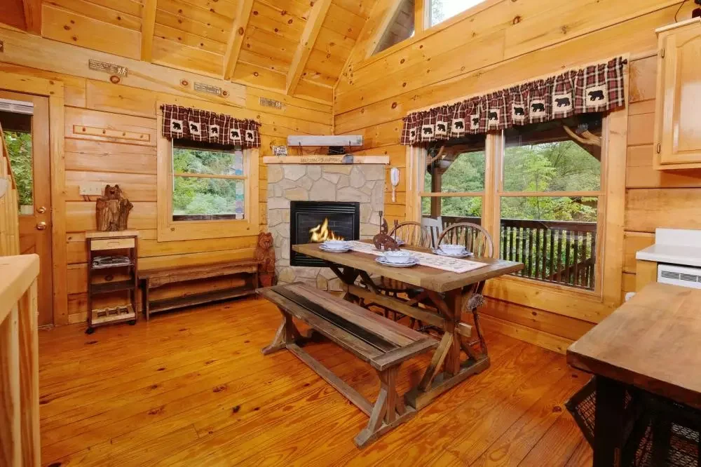 Dining area with a stone fireplace inside Scooter Bears Den cabin in Gatlinburg