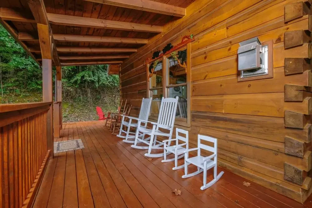 Covered wooden porch with rocking chairs at Scooter Bears Den