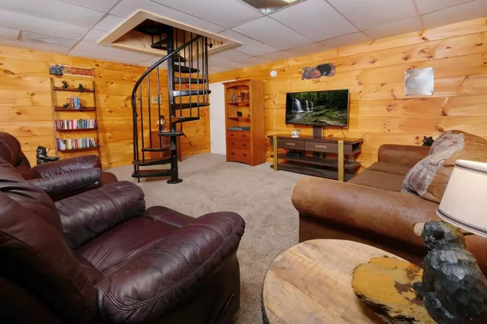 Downstairs living room with leather seating, TV, and spiral staircase