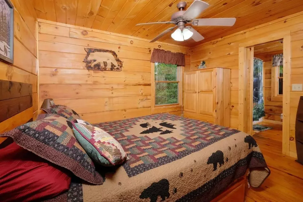 Cozy wood-paneled bedroom with bear-themed bedding at Scooter Bears Den